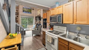 A modern kitchen with wooden cabinets, stainless steel appliances, and a dining area with a table and chairs. - Updated Studio in Elkhorn Village, Sun Valley (Sun Valley)