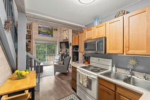 A modern kitchen with wooden cabinets, stainless steel appliances, and a dining area with a table and chairs. - Updated Studio in Elkhorn Village, Sun Valley (Sun Valley)