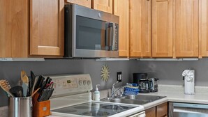A kitchen with wooden cabinets, a stainless steel microwave, a stove, a sink, and a dishwasher. - Updated Studio in Elkhorn Village, Sun Valley (Sun Valley)