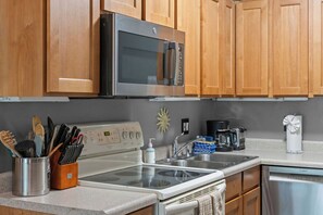 A kitchen with wooden cabinets, a stainless steel microwave, a stove, a sink, and a dishwasher. - Updated Studio in Elkhorn Village, Sun Valley (Sun Valley)