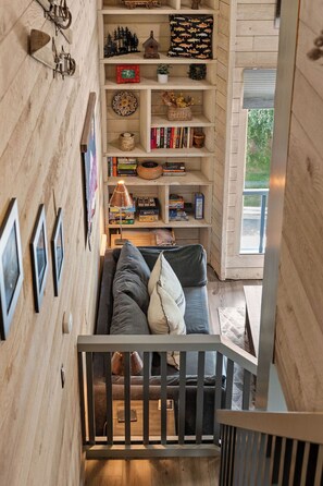A cozy interior with a wooden staircase leading to a living area, a sofa with cushions, and a bookshelf filled with books and decorative items. - Updated Studio in Elkhorn Village, Sun Valley (Sun Valley)