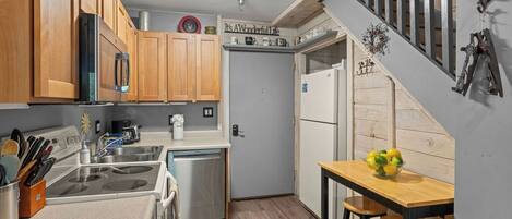 Eine Küche mit Holzausbau, einem Edelstahl-Kühlschrank, einem Geschirrspüler und einem Holztisch mit zwei Barhocker.