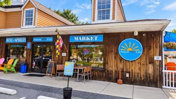Un bâtiment en bois avec une enseigne indiquant « Chesapeake Market & deli », un petit espace extérieur aménagé avec des sièges et un drapeau.