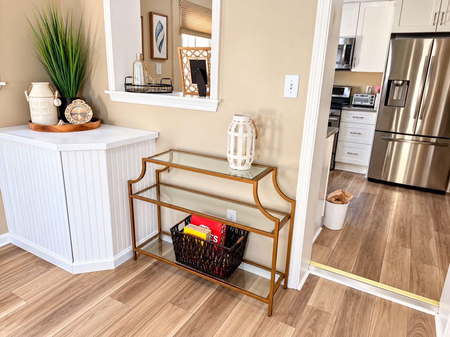 A kitchen with a white countertop, a stainless steel refrigerator, and a wooden floor.