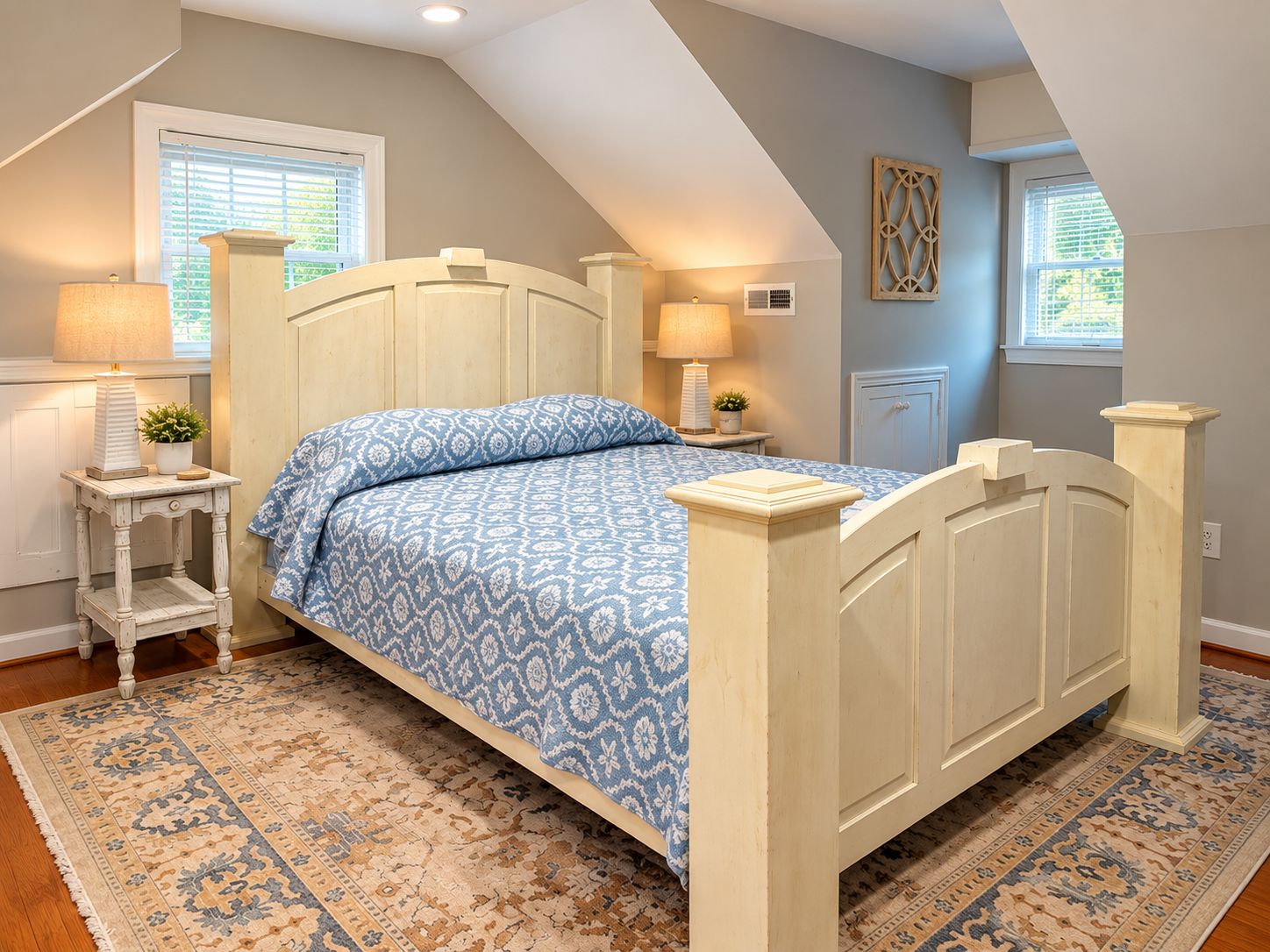 A bedroom with a bed, bedside tables, lamps, a rug, and a window with blinds.