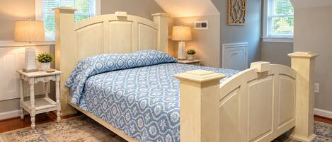 A bedroom with a bed, bedside tables, lamps, a rug, and a window with blinds.