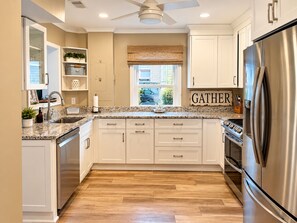 A modern kitchen with white cabinets, a stainless steel refrigerator, and a window with a view of the outside.