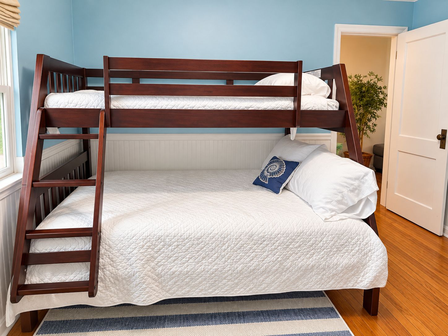A bunk bed with a wooden frame, white bedding, and a blue pillow with a floral design.