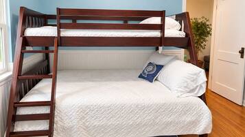 A bunk bed with a wooden frame, white bedding, and a blue pillow with a floral design.