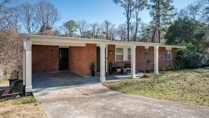 A single-story brick house with a covered porch, a garage, and a small front yard. - Stylish 5BR Retreat Near Airport & Downtown (Atlanta)