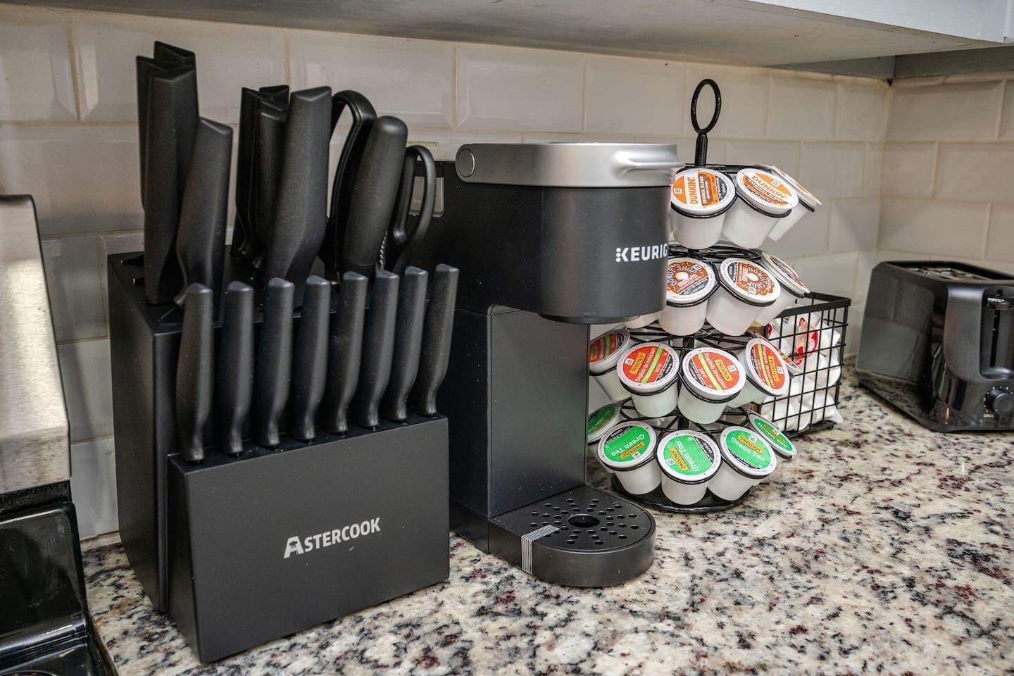 Eine Küche mit einem Messerblock, einem Topf, einem Toaster und einem Regal voller Joghurtbecher.