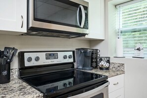 Une cuisine équipée d’une cuisinière, d’un four à micro-ondes, d’une machine à café et d’ustensiles de cuisine.