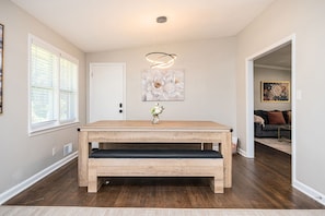 A dining area with a wooden table, benches, a vase with flowers, and a ceiling light fixture. - Stylish 5BR Retreat Near Airport & Downtown (Atlanta)