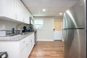 A modern kitchen with white cabinets, a stainless steel refrigerator, and a granite countertop.