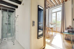 Een modern interieur met een glazen douche, een eethoek met natuurlijk licht en uitzicht op de stad.