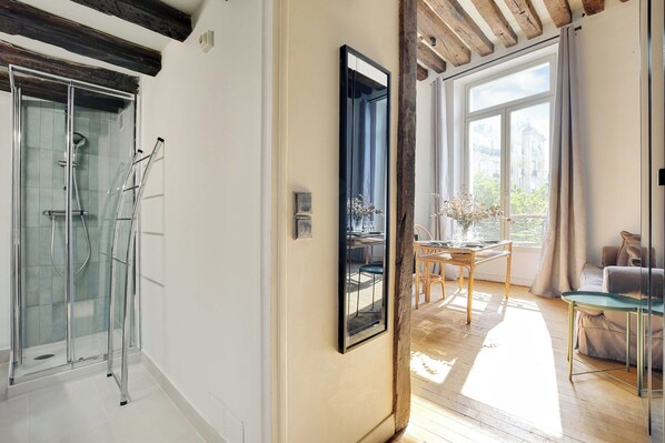 Un interior moderno con ducha de vidrio, comedor con luz natural y vistas a la ciudad.