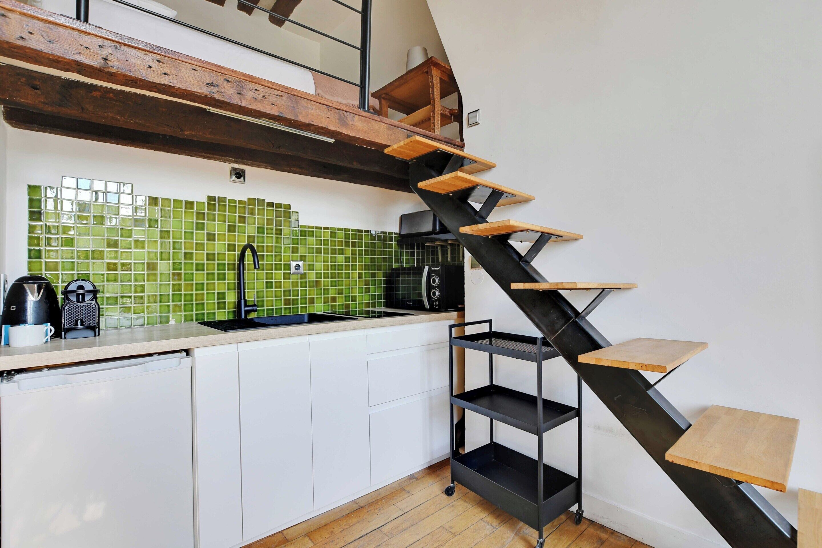 Een keuken met een modern design, voorzien van een zwarte trap met houten treden, een spoelbak en een betegelde achterwand.
