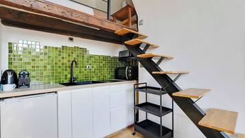 Een keuken met een modern design, voorzien van een zwarte trap met houten treden, een spoelbak en een betegelde achterwand.