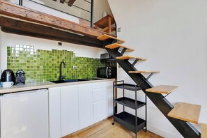 Een keuken met een modern design, voorzien van een zwarte trap met houten treden, een spoelbak en een betegelde achterwand.