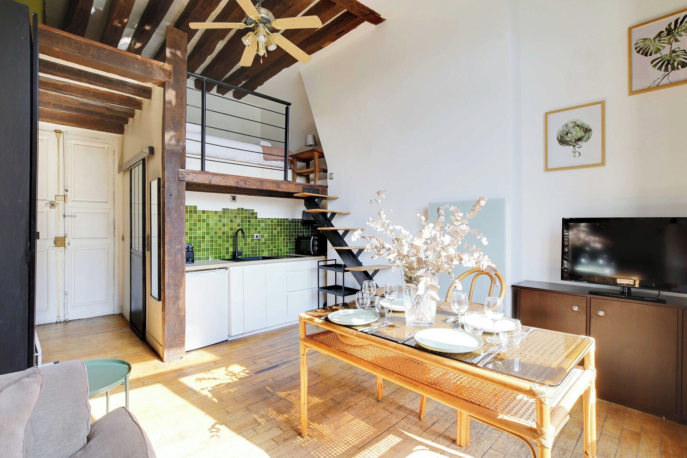 Un espacio habitable compacto con comedor, cocina y televisor.