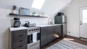 Una cocina moderna con horno empotrado, cafetera y microondas sobre la encimera.