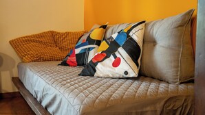A sofa with a quilted cover and two decorative pillows, one with a polka dot pattern and another with a solid color.