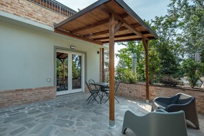 A covered patio with stone flooring, a table with chairs, and a wooden pergola structure.
