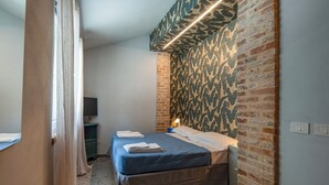 A bedroom with a bed, a TV, and a brick wall.