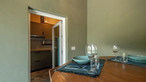 A dining area with a wooden table, two blue plates, a wine glass, and a water glass.