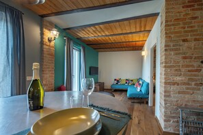 A dining area with a table set for two, a bottle of wine, and a glass.