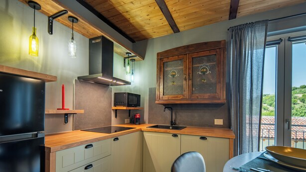 A compact kitchen with a built-in microwave, a stove, and a sink. There is a dining area with a table and chairs.