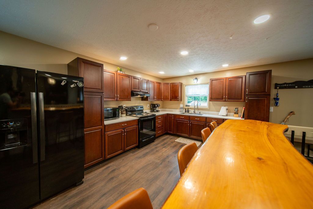 A modern kitchen with wooden cabinets, a black refrigerator, and a wooden dining table.