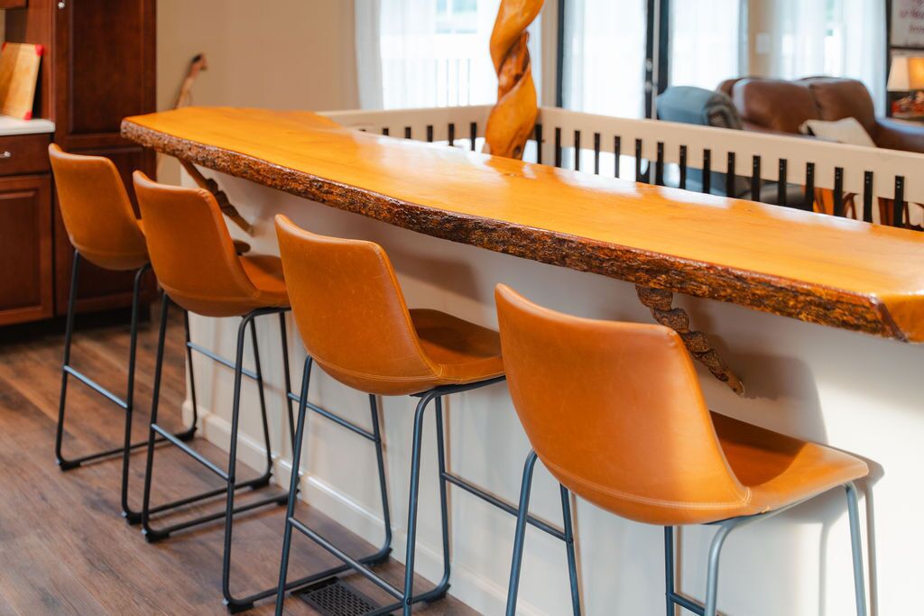 A bar area with a long wooden counter and four orange bar stools.