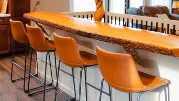 A bar area with a long wooden counter and four orange bar stools.