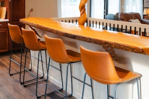 Eine Bar mit einer langen Holztheke und vier orangefarbenen Barhocker.