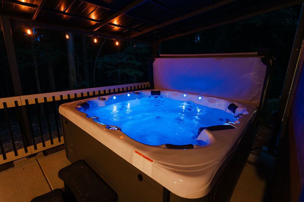 Ein Whirlpool mit erhöhtem Rand und einer Sitzbank davor, umgeben von einer Holzterrasse und einem Geländer.