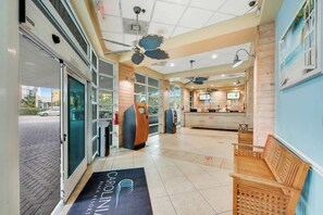 A hotel lobby with a reception desk, seating area, and a view of the street outside. - Carolinian Beach Resort 1036 (Myrtle Beach)