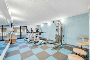 A gym with cardio machines, weight benches, and a mirrored wall. - Carolinian Beach Resort 1036 (Myrtle Beach)