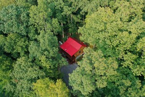 Eine Holzhütte mit rotem Dach, umgeben von dichtem Grünwald.