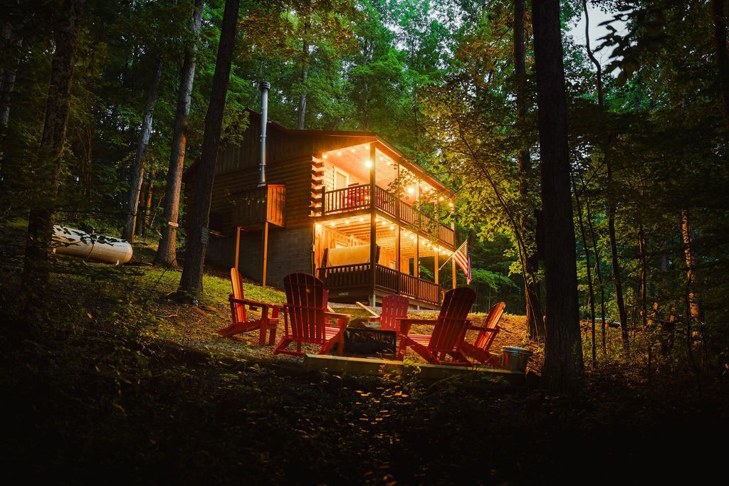 A cabin with a deck, surrounded by trees, and equipped with outdoor seating.
