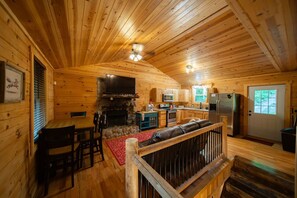 Ein Holzhütten-Interieur mit Essbereich, Küche und Kamin.