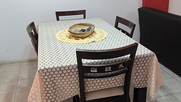A dining area with a table set for four, surrounded by chairs, a chandelier, and wall art.