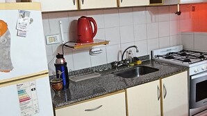A kitchen with a refrigerator, stove, sink, and cabinets.