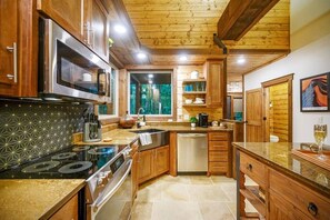 A kitchen with wooden cabinets, a stainless steel stove, and a dishwasher. - The Guesthouse: Romantic luxury retreat for two with forest views & a soaker tub (Broken Bow)