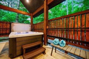 A hot tub in a wooden outdoor setting with a bench and towels. - The Guesthouse: Romantic luxury retreat for two with forest views & a soaker tub (Broken Bow)