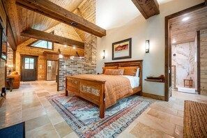 A spacious bedroom with a large bed, a fireplace, and a view of the outdoors. - The Guesthouse: Romantic luxury retreat for two with forest views & a soaker tub (Broken Bow)