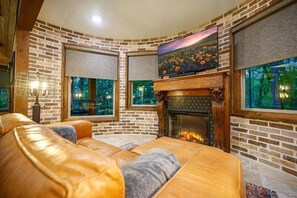 Ein gemütliches Wohnzimmer mit Kamin, Ledersofa und großen Fenstern.