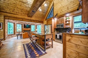 Ein Holzblockhaus-Interieur mit Küche, Essbereich und großen Fenstern.