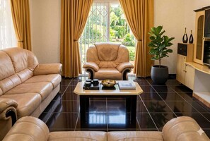Ein Wohnzimmer mit einer Ledersofa, einem passenden Sessel, einem Couchtisch mit Dekoration und einer Topfpflanze.