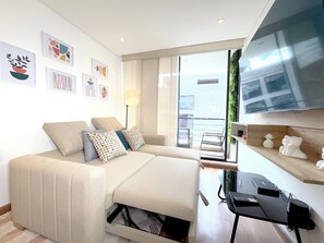 Ein modernes Wohnzimmer mit einer Couch, einem Couchtisch und einem an der Wand befestigten Fernseher.